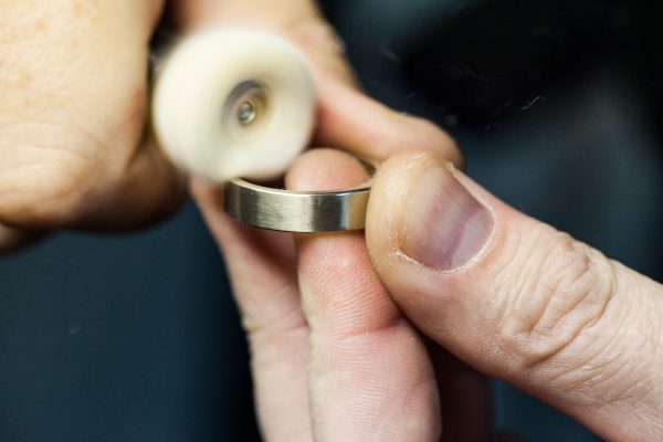 a photograph of a pair of hands polishing a silver ring