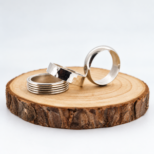a trio of chunky silver rings sitting on a wooden background